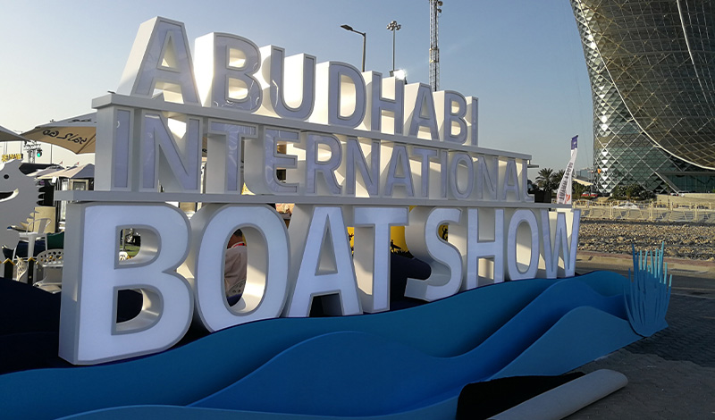 a sign of white letters saying abu dhabi international boat show
