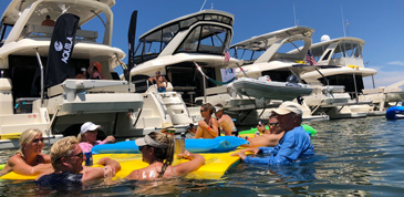 group of people standing in shallow water behind a raft up of Aquila catamarans