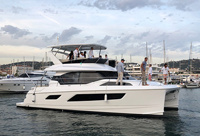 An Aquila power catamaran anchored in a marina in Cannes France with several people aboard