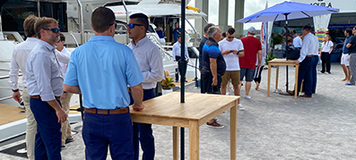 People standing at the Miami Boat Show near Aquila Power Catamarans and talking