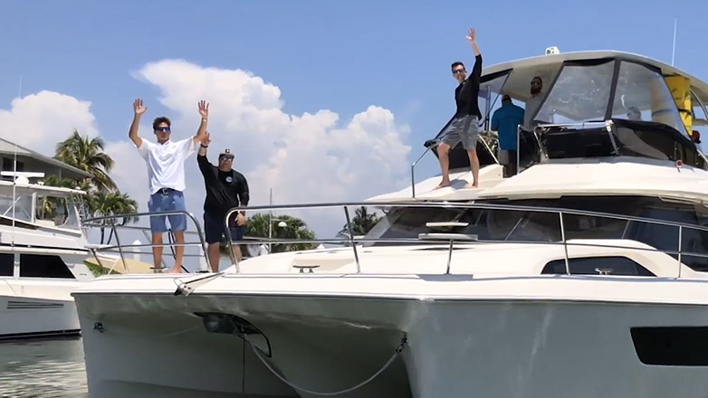 People waving hello aboard an Aquila catamaran during the 2018 Owners Rendezvous