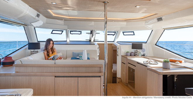 Woman relaxing in interior of Aquila 44 catamaran
